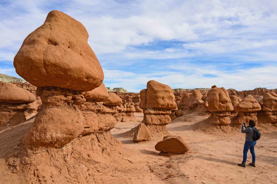 <p>Dermot Conlan/Getty Images</p> Hiker taking photos in Goblin Valley State Park.