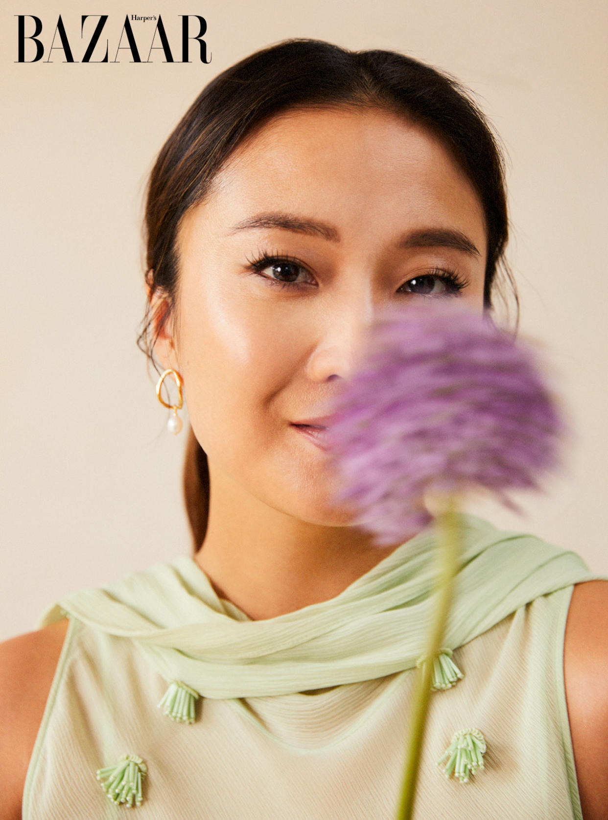 Ashley Park in a green top with a purple flower in front of her face