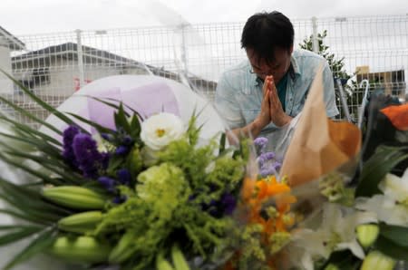 A man prays next to the flowers dedicated to the victims of the fire, near the Kyoto Animation building which was torched by arson attack, in Kyoto