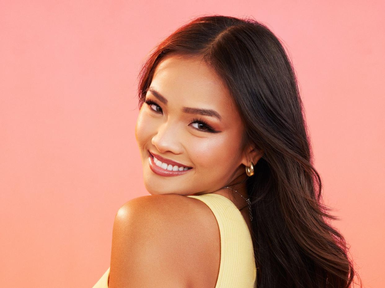 Jenn poses for photos in a yellow dress, gold earrings, and silver bracelet.