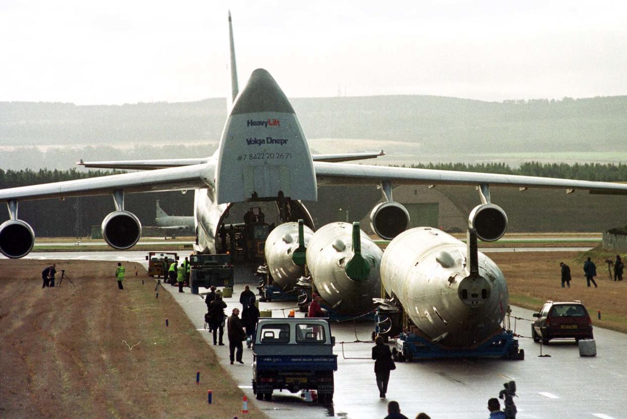 A  Russian Antonov 124 condor freighter sits on a tarmac with its nose opened to accept cargo.