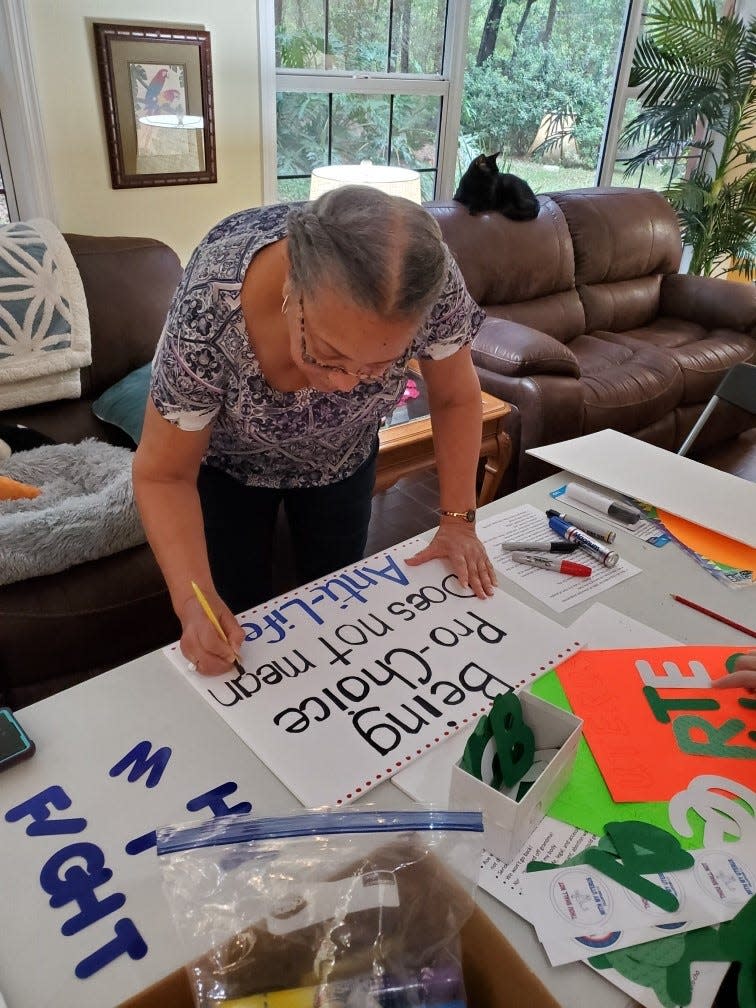 Debra Williams letters a sign for upcoming pro-choice events in Volusia County on Friday and Saturday.