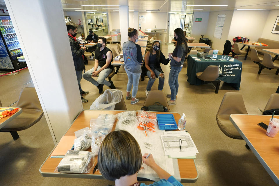 Workers with Peninsula Community Health Services, give patients the first shot of the Pfizer COVID-19 vaccine, Tuesday, May 25, 2021, in the galley area of a Washington state ferry sailing from Bremerton, Wash. to Seattle. Tuesday was the first day of several dates that the vaccine would be offered to people on ferry sailings between the two cities. (AP Photo/Ted S. Warren)