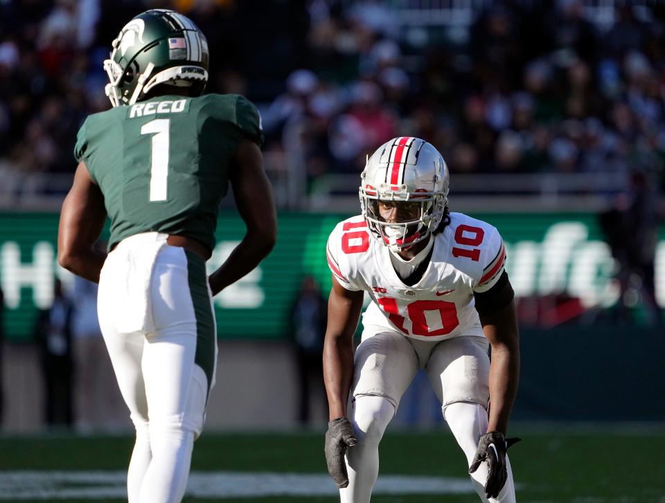 Oct 8, 2022; East Lansing, Michigan, USA; Ohio State Buckeyes cornerback Denzel Burke (10) goes up against Michigan State Spartans wide receiver Jayden Reed (1) in the third quarter of the NCAA Division I football game between the Ohio State Buckeyes and Michigan State Spartans at Spartan Stadium. 