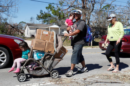 Lazaro and Amanda Perez, of Callaway, walk home with their children after picking up food and water from a public distribution location in Parker, Florida, U.S., October 13, 2018. REUTERS/Terray Sylvester