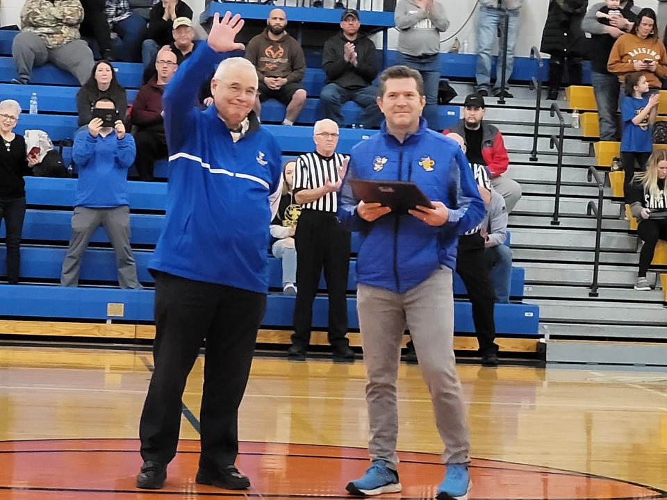 East Canton athletic director and baseball coach Doug Miller waves to the crowd before superintendent Kevin Finefrock presents him with a plaque Tuesday night. Miller is retiring as AD at the end of the school year, but still plans to coach baseball at East Canton.