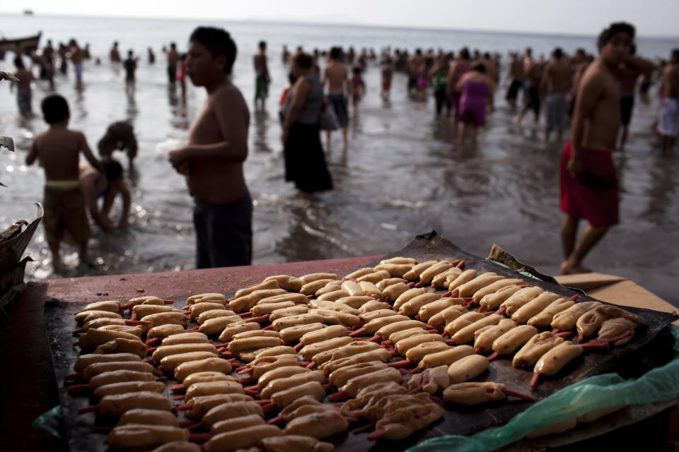 In this Jan. 13, 2013 photo, uncooked bread covered sausage called "Caramandunga," cooked on the spot for clients in a small portable oven, are display on Agua Dulce beach in Lima, Peru. While Lima's elite spends its summer weekends in gate beach enclaves south of the Peruvian capital, the working class jams by the thousands on a single municipal beach of grayish-brown sands and gentle waves. The only barrier to entry to "Agua Dulce" beach is two dollars, the price of bus fare to get there and home. (AP Photo/Rodrigo Abd)