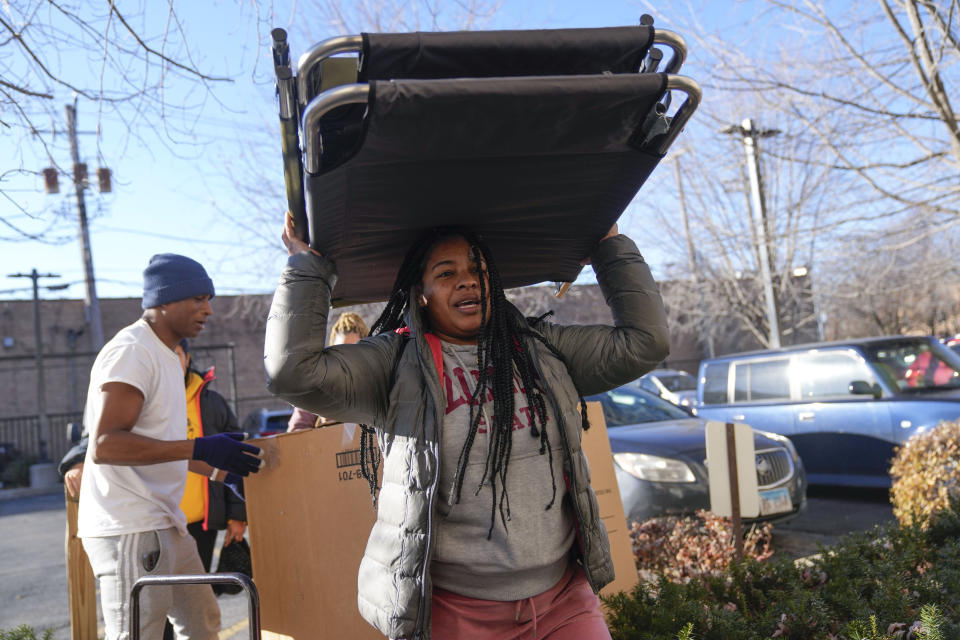 Yimara Pajaro of Venezuela carries cots into the Chicago City Life Center Wednesday, Nov. 29, 2023, in Chicago. The community center and church welcomed about 40 migrants who were previously living at police stations and airports. (AP Photo/Erin Hooley)