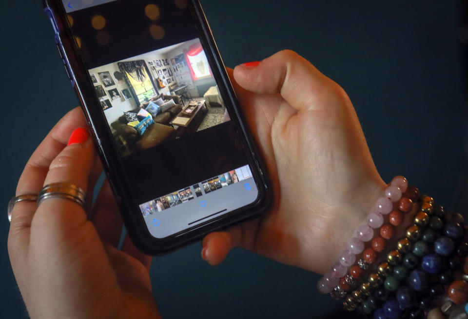 Rachel Berry shows a cellphone photo of her living room before a makeover with her art, Monday, July 6, 2020, in New York. Before the coronavirus pandemic, Berry worked as a bartender and waited tables, jobs that gave her enough time to work on her creative pursuits. But as New York City tries to reopen, there's concern that jobs for the city's creative class are no longer readily available. (AP Photo/Bebeto Matthews)