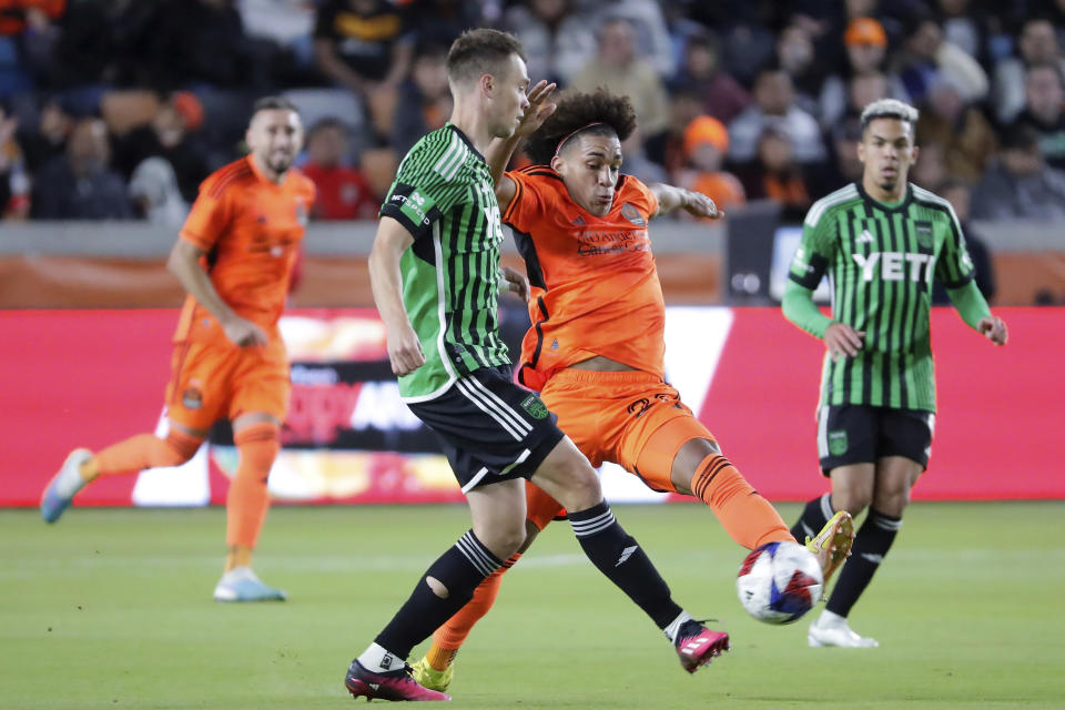 Austin FC defender Leo Vaisanen, center left, kicks away as Houston Dynamo midfielder Adalberto Carrasquilla, center right, attempts to block the pass during the second half of an MLS soccer match Saturday, March 18, 2023, in Houston. (AP Photo/Michael Wyke)