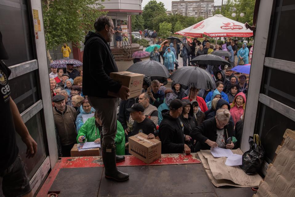 Residents in Kherson gather to collect food and humanitarian aid on Sunday after flooding from explosion of the Kakhovka dam and hydroelectric power plant left the region submerged, and thousands without any power and water. (Getty Images)