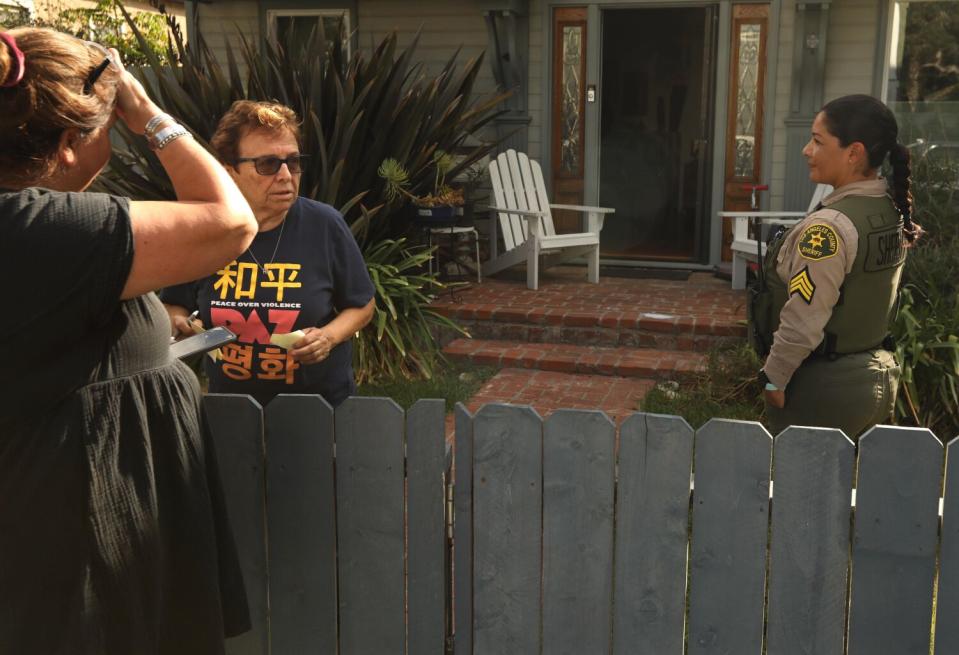 A woman talks to another woman by a fence