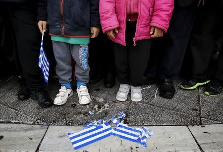 A paper flag is seen on the payvment as Greek children watch a military parade during Independence Day celebrations in Athens, March 25, 2015. REUTERS/Yannis Behrakis