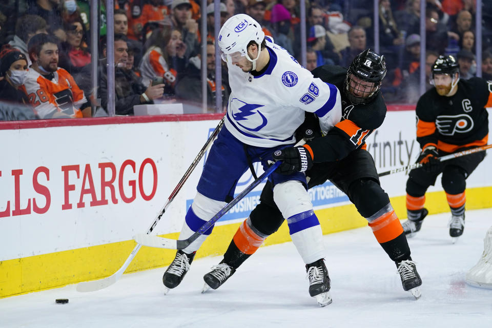 Tampa Bay Lightning's Mikhail Sergachev (98) keeps Philadelphia Flyers' Sean Couturier (14) away from the puck during the second period of an NHL hockey game, Sunday, Dec. 5, 2021, in Philadelphia. (AP Photo/Matt Slocum)