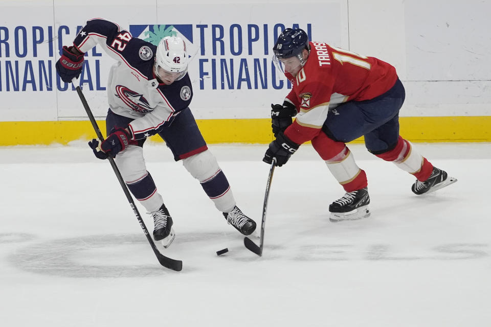 Columbus Blue Jackets center Alexandre Texier (42) and Florida Panthers right wing Vladimir Tarasenko (10) go after a puck during the first period of an NHL hockey game, Thursday, April 11, 2024, in Sunrise, Fla. (AP Photo/Marta Lavandier)