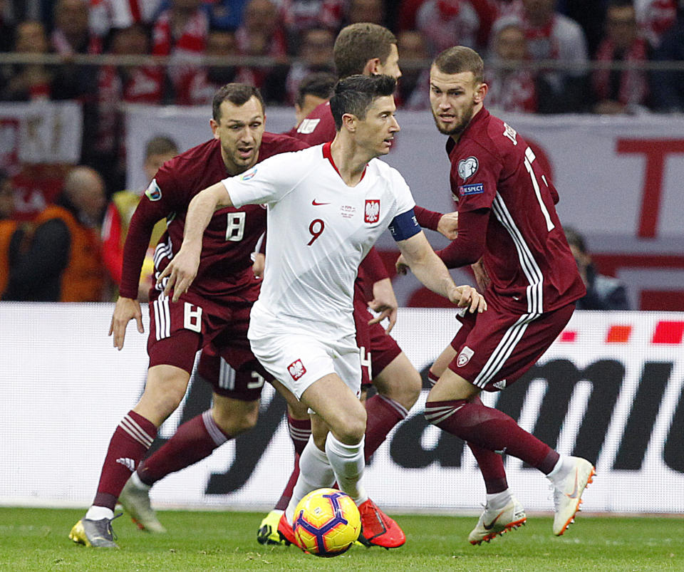Poland's Robert Lewandowski, center, and Latvia's Olegs Laizans, left, and Ritvars Rugins, right,challenge for the ball during the Euro 2020 group G qualifying soccer match between Poland and Latvia at the National stadium in Warsaw,Poland, Sunday, March 24, 2019.(AP Photo/Czarek Sokolowski)