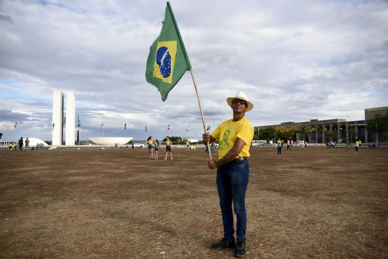 Un simpatizante de Jair Bolsonaro sostiene una bandera de Brasil mientras espera los resultados tras el cierre de urnas en la segunda vuelta de las elecciones presidenciales en Brasilia, Brasil, el domingo 30 de octubre de 2022