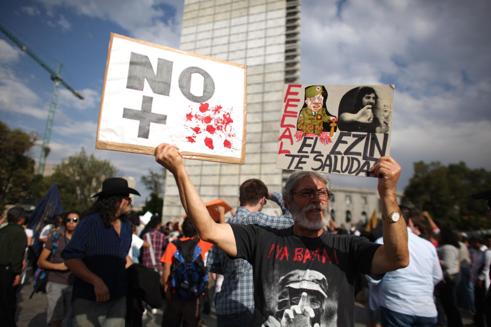 A man holds up banners during a protest against a possible return of the old ruling Institutional Revolutionary Party (PRI) in Mexico City, Wednesday, May 23, 2012. Demonstrators also protested against what students perceive as a biased coverage by major Mexican TV networks of the presidential elections campaign, which they claim to be directed in favor of PRI's candidate Enrique Pena Nieto. Mexico will hold presidential elections on July 1. (AP Photo/Alexandre Meneghini)