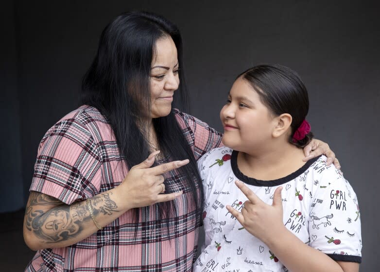 CANOGA PARK, CA - November 22, 2021: Rena Tafoya, 48 and her daughter, Maya Flores, 11, who is a deaf student enrolled in LAUSD'S City of Angels independent study program, are photographed in front of their home in Canoga Park. They are signing, "I Love You," to each other, something they do every night before going to bed. Rena tried to get her daughter an ASL interpreter, but it took more than 2 months. Children like Maya, who require services under their Individualized Education Plan, are being left behind by independent study programs, which became the only official distance learning program this year. (Mel Melcon / Los Angeles Times)