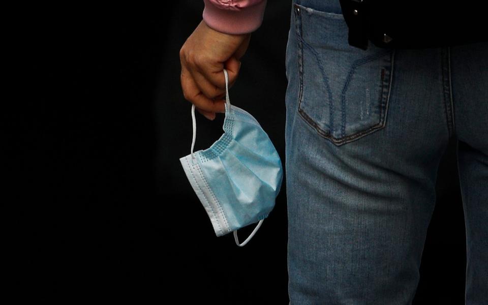 A woman holding her face mask walks into an underpass tunnel in Beijing - Andy Wong / AP