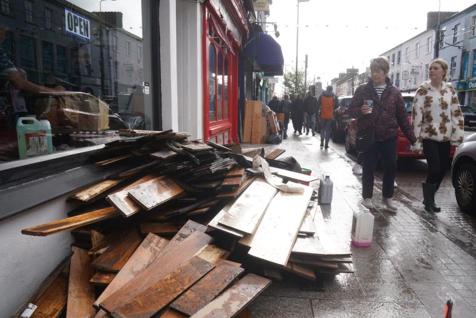 People walk past damaged shops on Main street in Midleton, Co Cork (PA)