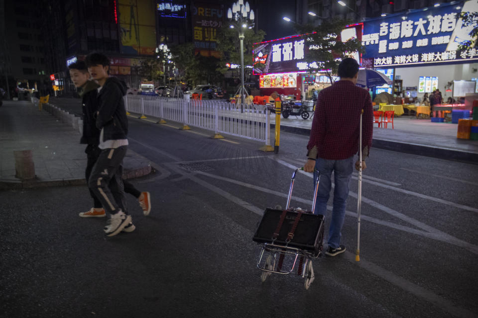 In this Dec. 6, 2019, photo, Wu Yi, who has struggled with Oxycontin abuse, crosses a street while on his way to sing songs for money at all night-restaurants and clubs in Shenzhen in southern China's Guangdong Province. Officially, pain pill abuse is an American problem, not a Chinese one. But people in China have fallen into opioid abuse the same way many Americans did, through a doctor's prescription. And despite China's strict regulations, online trafficking networks, which facilitated the spread of opioids in the U.S., also exist in China. (AP Photo/Mark Schiefelbein)
