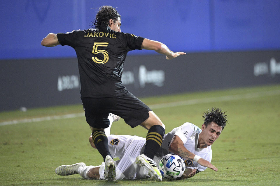 Los Angeles FC defender Dejan Jakovic (5) and LA Galaxy forward Cristian Pavon compete for the ball during the first half of an MLS soccer match Saturday, July 18, 2020, in Kissimmee, Fla. (AP Photo/Phelan M. Ebenhack)