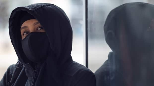 A person wearing a mask sits in a bus shelter in late April 2021. On Sunday, Ottawa's health officials reported 143 new cases of COVID-19 and two deaths.  (Andrew Lee/CBC - image credit)