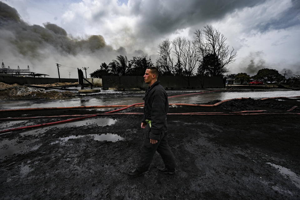 A firefighter walks on the site of a deadly fire at a large oil storage facility in Matanzas, Cuba, Tuesday, Aug. 9, 2022. The fire was triggered when lighting struck one of the facility's eight tanks late Friday, Aug. 5th. (Yamil Lage, Pool photo via AP)