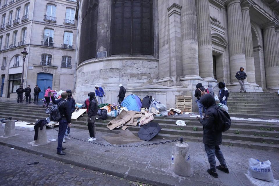 Miigrants pack their belongings while being evicted from a makeshift camp, Tuesday, April 30, 2024 in Paris. Similar operations are carried out by the police authorities on a daily basis in the months leading to the Olympics. (AP Photo/Michel Euler)