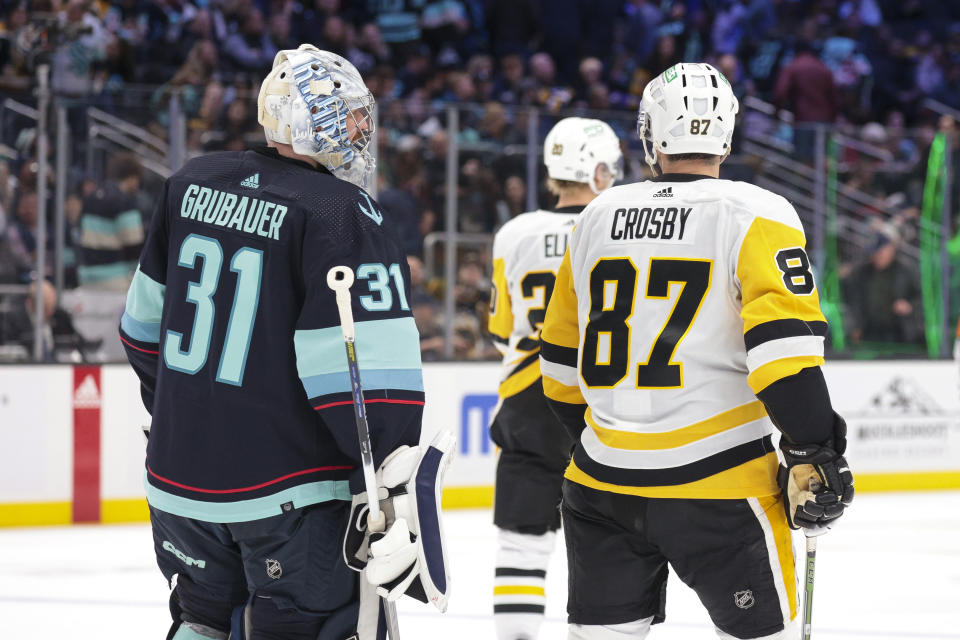 Pittsburgh Penguins center Sidney Crosby (87) speaks to Seattle Kraken goaltender Philipp Grubauer (31) as they head off ice following the second period of an NHL hockey game Thursday, Feb. 29, 2024, in Seattle. (AP Photo/Jason Redmond)