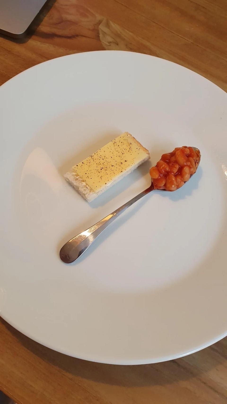 A plate with a cheese-topped cracker and a spoonful of baked beans