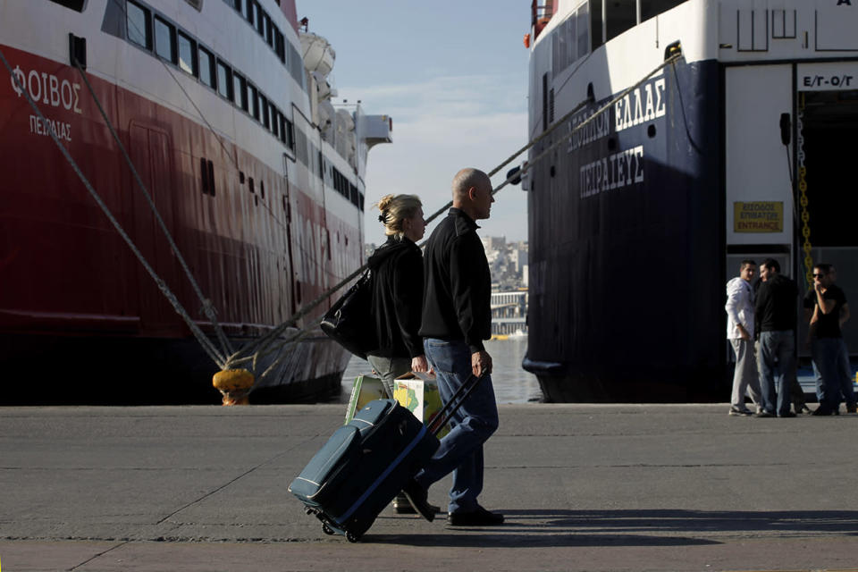 Tourists carry their luggage as their pass in front of docked ships at the port of Piraeus, near Athens during a 48-hour nationwide general strike.