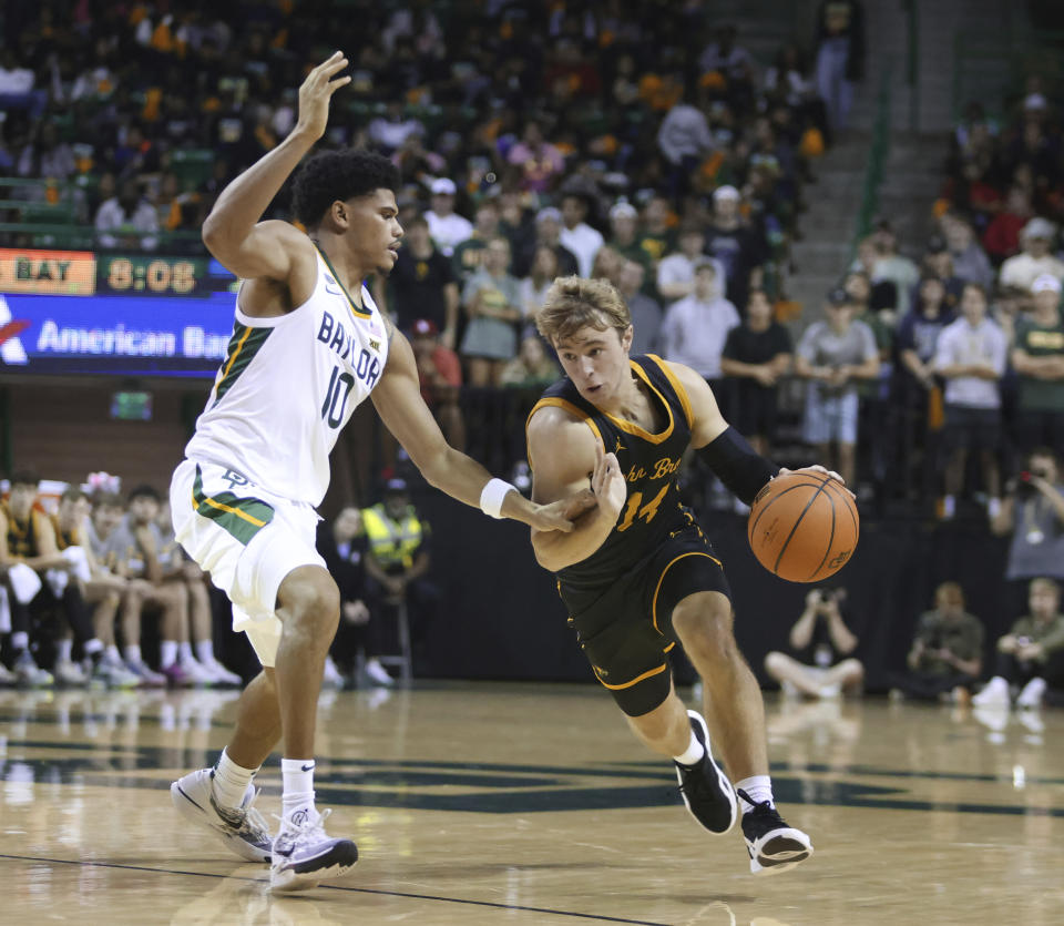 John Brown guard Trae Oetting, right, drives past Baylor guard RayJ Dennis in the first half of an NCAA college basketball game, Thursday, Nov. 9, 2023, in Waco, Texas. (AP Photo/Rod Aydelotte)