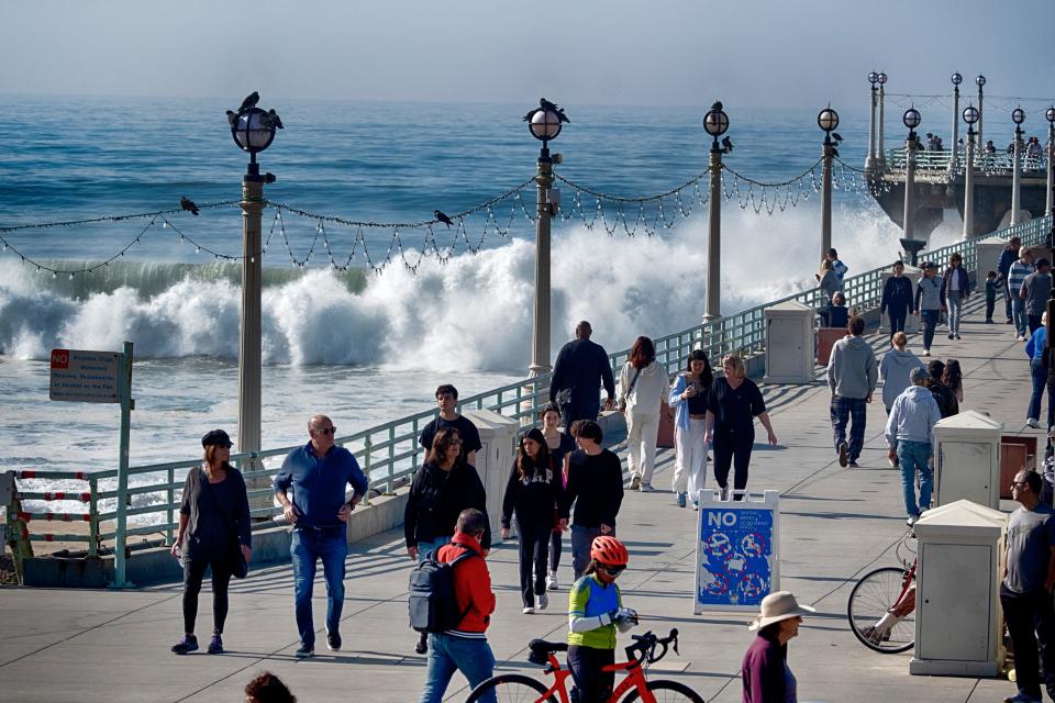 Visitors to Manhattan Beach pier watch as turbulent surf pounds the side of the pier in Manhattan Beach, Calif. on Thursday, Dec. 28, 2023. Powerful surf rolled onto beaches on the West Coast and Hawaii on Thursday as a big swell generated by the stormy Pacific Ocean pushed toward shorelines, causing localized flooding.