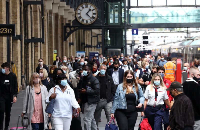 People wearing protective face masks walk along a platform at King's Cross Station, amid the coronavirus disease (COVID-19) outbreak in London