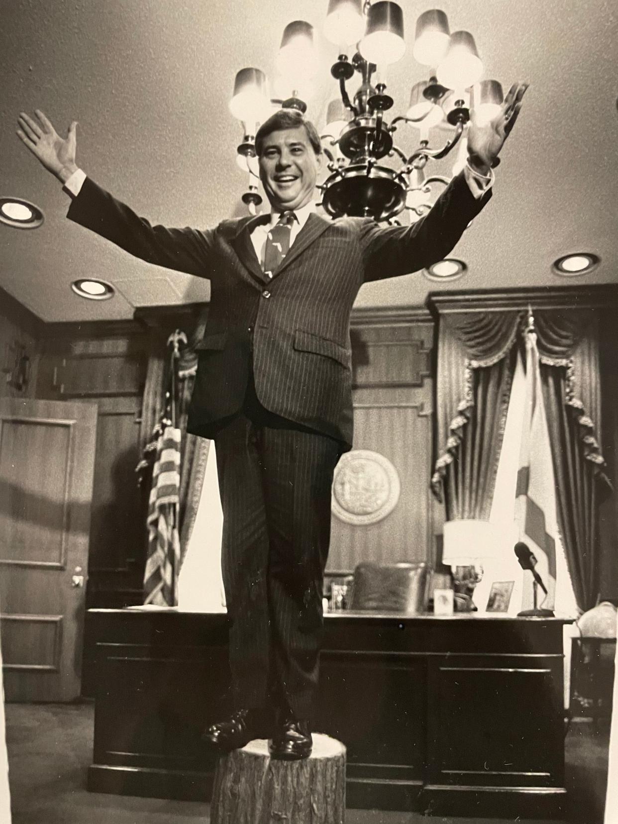 Former Florida Gov. Bob Graham stands on a cypress stump and delivers a stunning rendition of his campaign song for the press and the Tallahassee Jaycees in his office Monday. The event was to publicize the Jaycee's Cracker Days on Sept. 11 and 12.