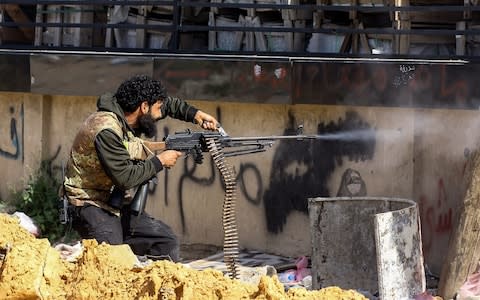 A Libyan fighter loyal to the Government of National Accord (GNA) fires a machine gun during clashes with forces loyal to strongman Khalifa Haftar south of the capital Tripoli's suburb of Ain Zara, on April 10, 2019 - Credit: Mahmud Turkia/AFP