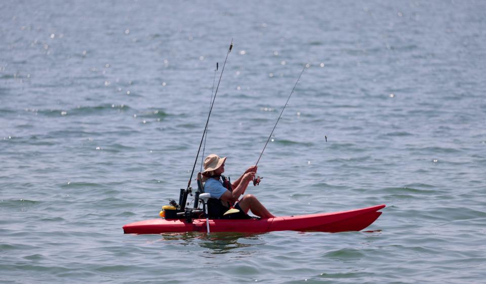 A fisherman enjoying a calm day on Lake St. Clair fishing  from his kayak at the Metropark in Harrison Township on Wednesday, July 19, 2023. 