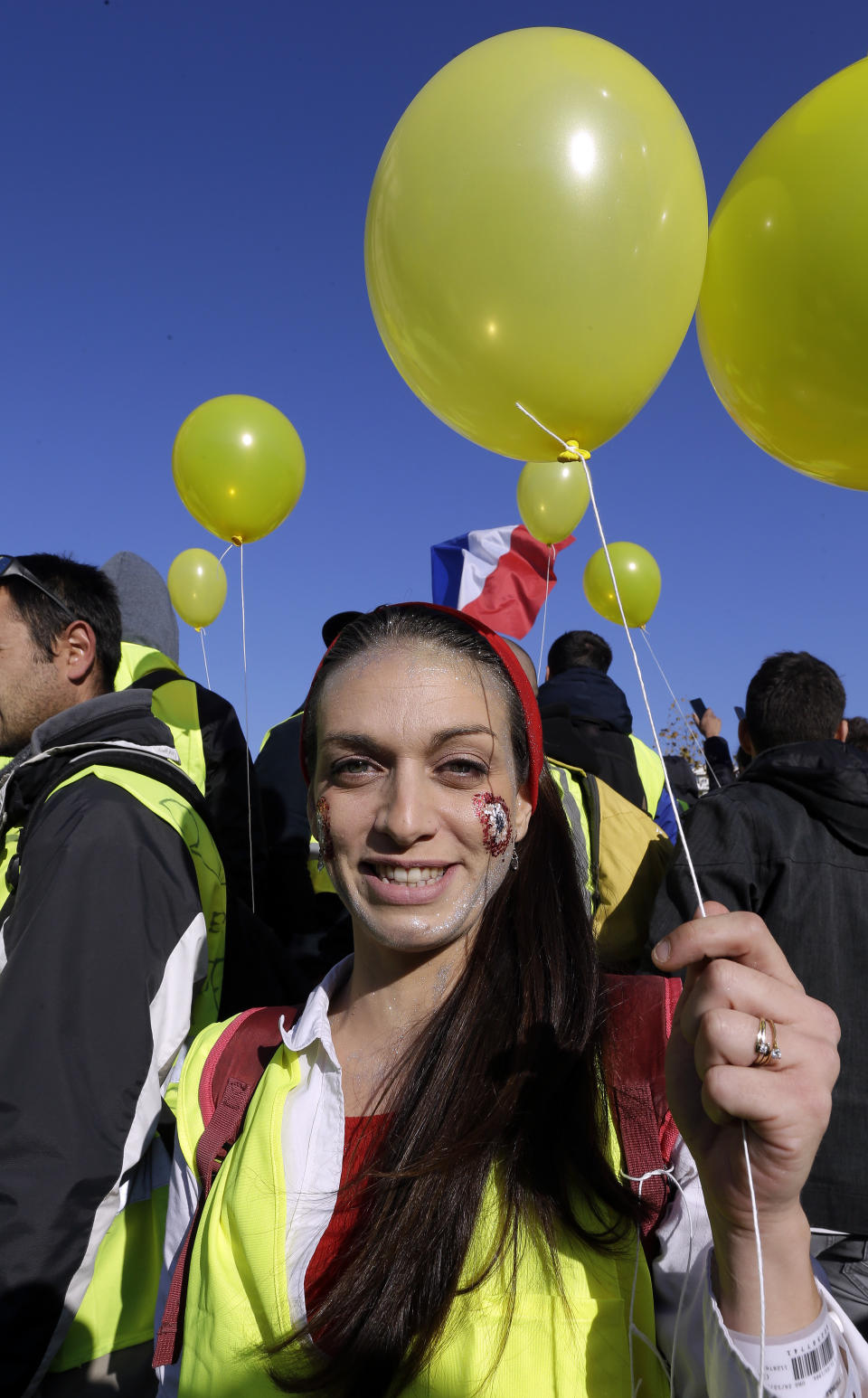 A demonstrator with a yellow balloon and wearing her yellow vest demonstrates during a protest in front of the Arc de Triomphe of the Porte d'Aix, in Marseille, southern France, Saturday, Dec. 29, 2018. The yellow vest movement held several peaceful demonstrations in cities and towns around France, including about 1,500 people who marched through Marseille. (AP Photo/Claude Paris)