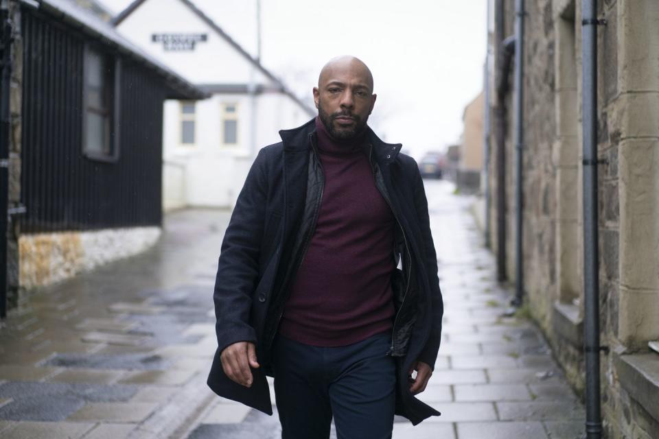 john howell, played by don gilet, walks down a street in a scene from shetland