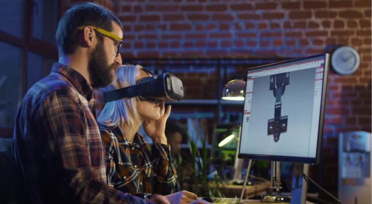 Woman in VR glasses and man sitting at computer and creating graphics of modern video game.