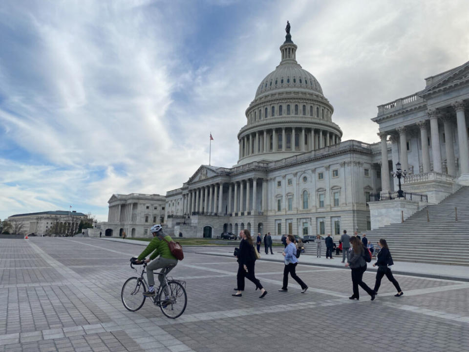 People walking and biking in front of the U.S. Capitol.