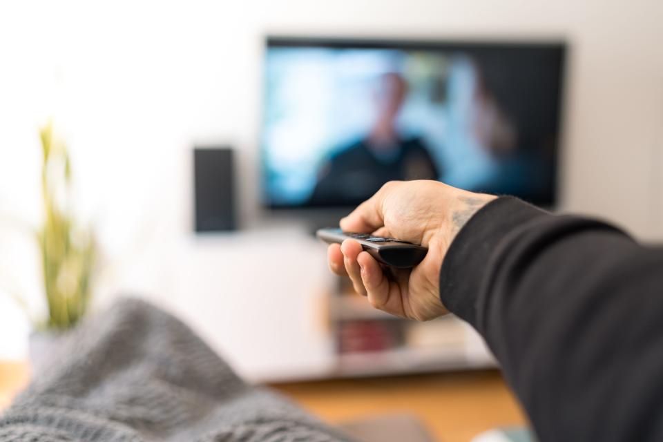 A hand holds a tv remote