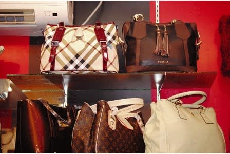 A shop assistant displays a fake Louis Vuitton bag at a store in