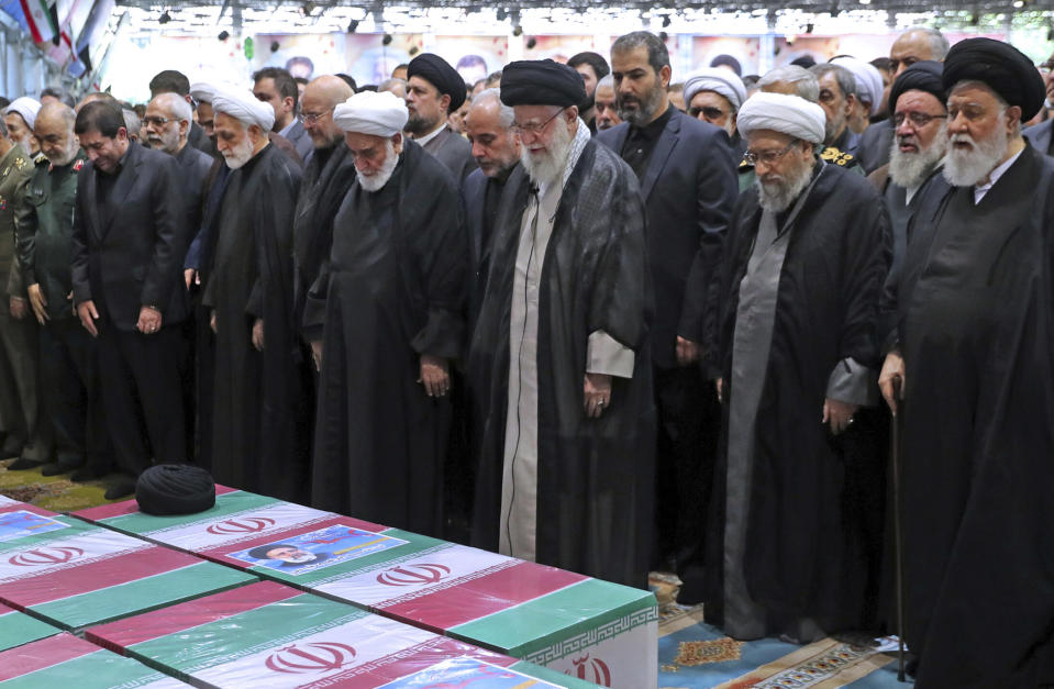 En esta foto publicada por la oficina del líder supremo de Irán, el ayatolá Alí Jamenei, en el centro, con turbante negro, lidera una oración sobre los ataúdes envueltos en banderas iraníes del presidente del país, Ebrahim Raisi, y sus compañeros de viaje, fallecidos en un choque de helicóptero el domingo en una región montañosa del noroeste del país, en el campus de la Universidad de Teherán, durante un funeral en Teherán, Irán, el miércoles 22 de mayo de 2024. (Oficina del líder supremo de Irán via AP)