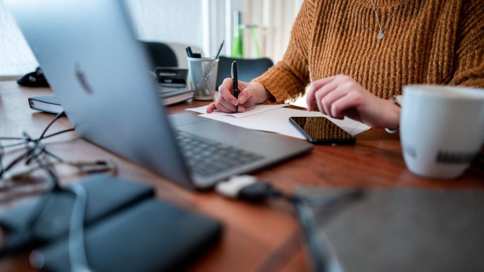 Eine Frau sitzt mit einem Laptop an einem Tisch im Homeoffice.