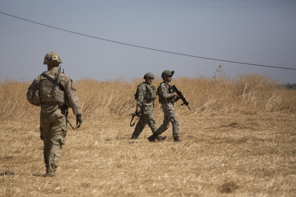 Turkish forces survey the so-called "safe zone" during their first joint ground patrol with U.S. forces on the Syrian side of the border with Turkey, seen in the background, near Tal Abyad, Syria, Sunday, Sept. 8, 2019. Turkey hopes the buffer zone, which it says should be at least 30 kilometers (19 miles) deep, will keep Syrian Kurdish fighters, considered a threat by Turkey but U.S. allies in the fight against the Islamic State group, away from its border. (AP Photo/Maya Alleruzzo)