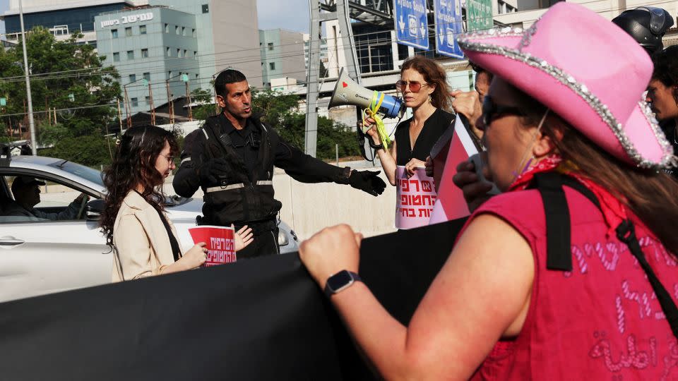 A police officer tries to disperse protesters demanding Israel's government accept the hostage deal on the highway into Tel Aviv. - Shannon Stapleton/Reuters