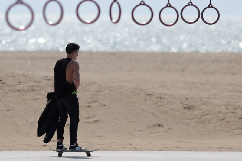 A man skateboards past exercise rings on the beach during the global outbreak of coronavirus disease (COVID-19) in Santa Monica